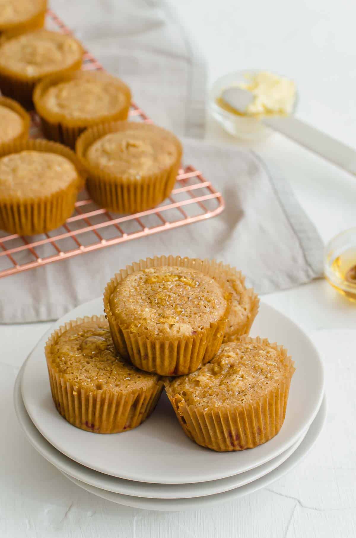 Four raspberry muffins on a white plate. 