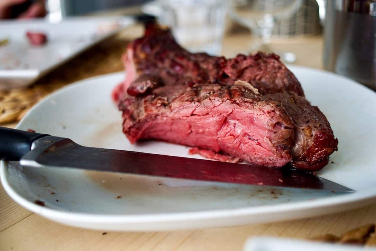 A piece of red meat on a white plate. 