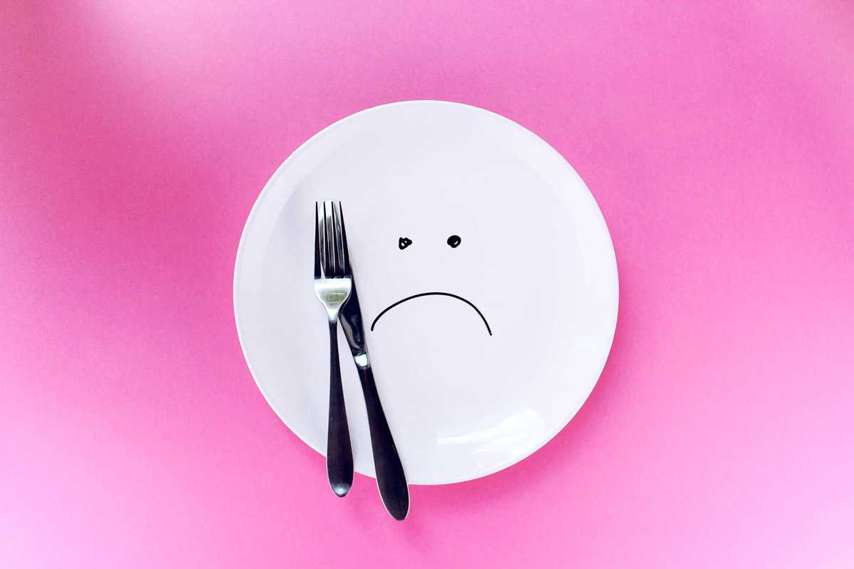 An empty plate with cutlery placed overtop to demonstrate how sad and restrictive intuitive fasting is. 