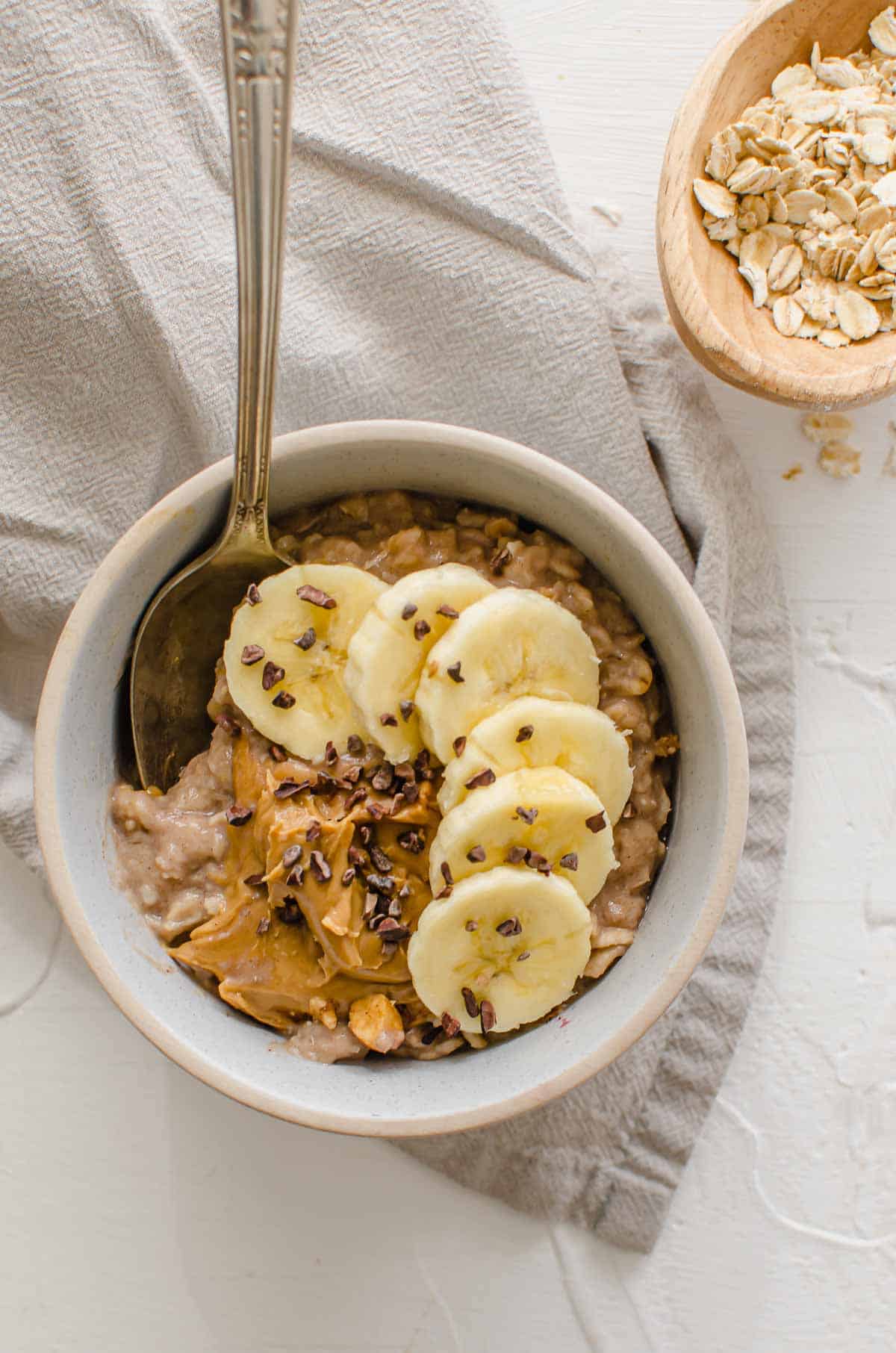 Birds eye view of protein oats topped with banana, peanut butter, and cacao nibs. 