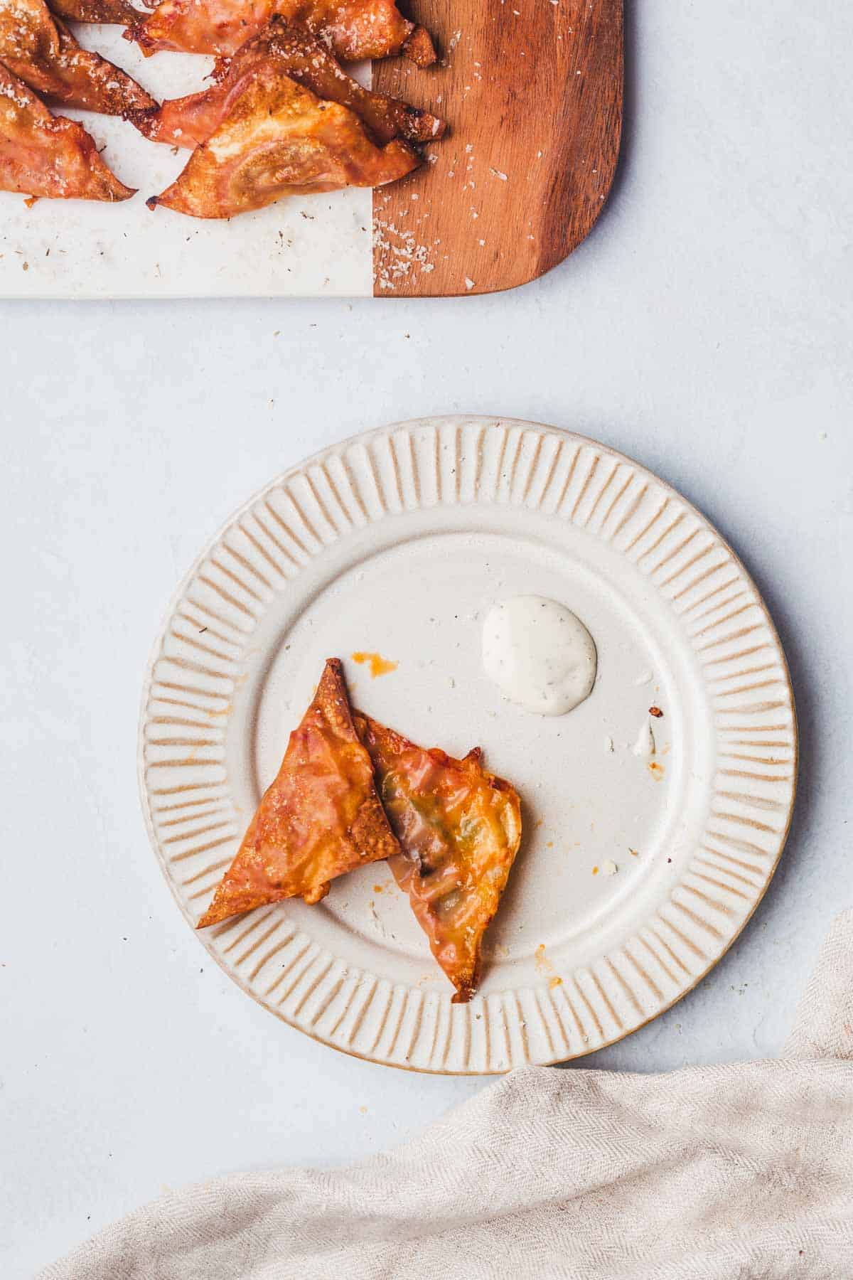 A plate with two air fried wonton wrapped pizzas with dipping sauce.