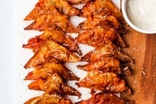 A serving board with multiple air fryer pizza rolls made with wonton wrappers.