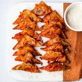 A serving board with multiple air fryer pizza rolls made with wonton wrappers.