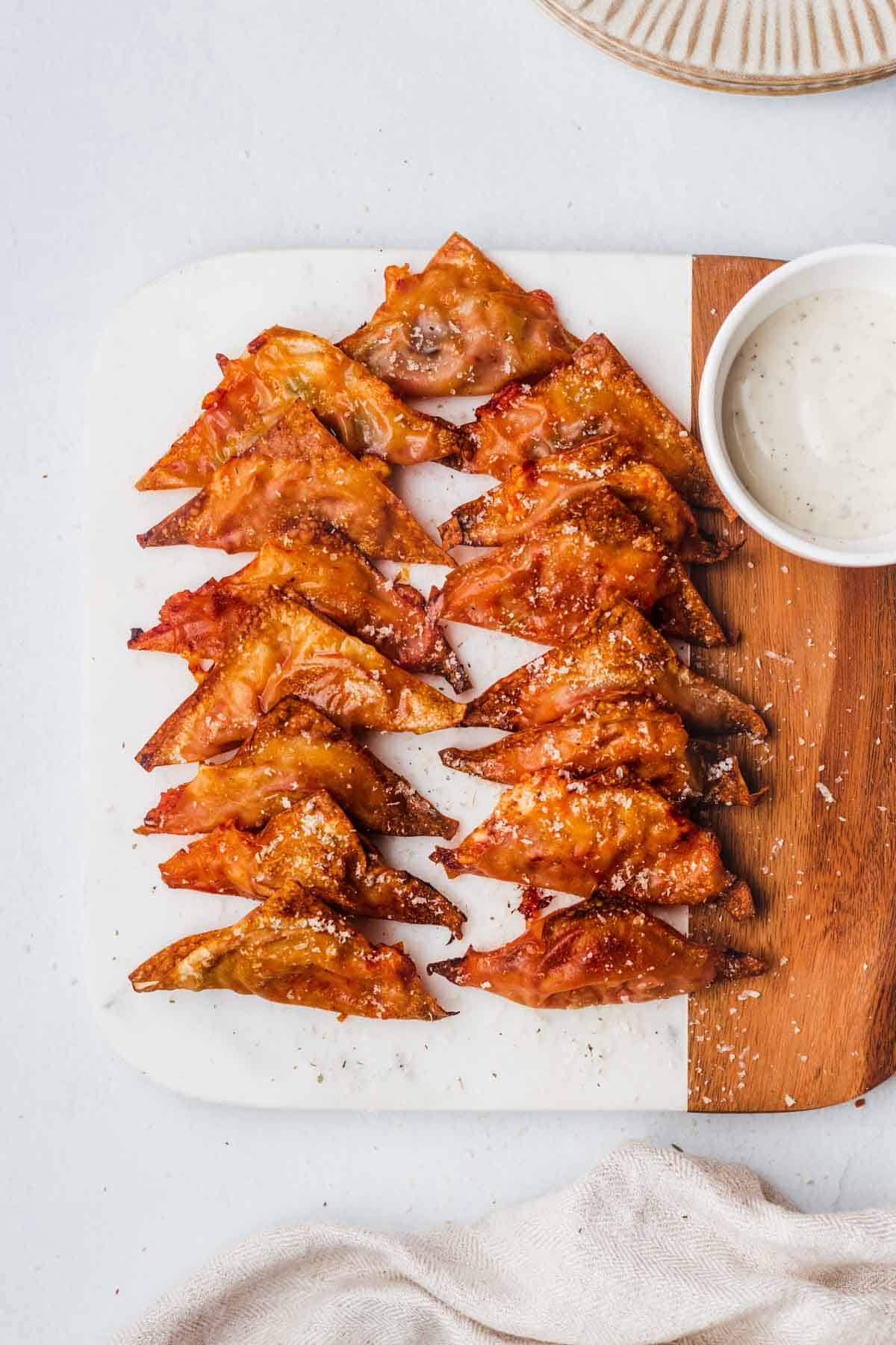 A serving board with multiple air fryer pizza rolls made with wonton wrappers.