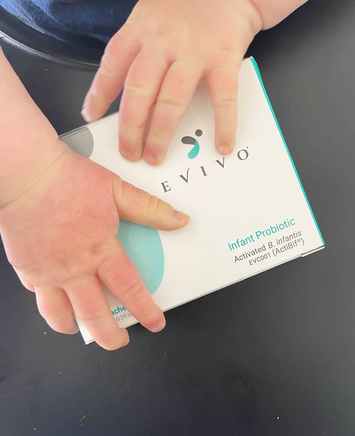 Baby hands holding Evivo probiotics. 