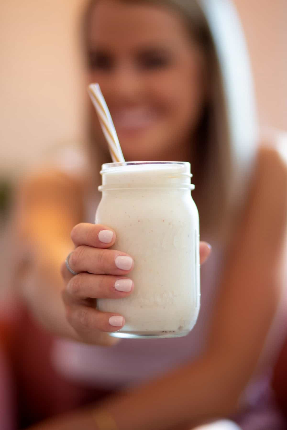 Woman holding up a jar of Beachbody shakeology supplement. 