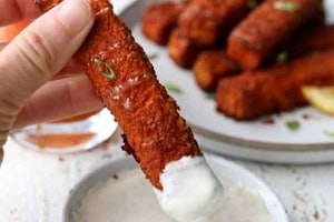 Pinterest graphic of a tofu stick being dipped into ranch with the text overlay "crispy baked buffalo tofu."