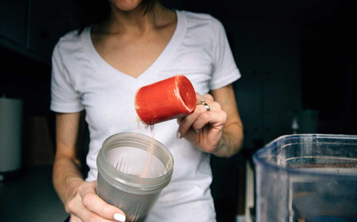 Woman pouring Beachbody shakeology powder in to a shaker. 