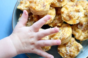 Pinterest graphic of a toddler's hand reaching for mac and cheese bites.