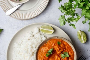 Pinterest graphic of a plate of rice with a bowl of vegan butter chicken.