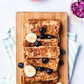 Overhead view of a serving board with a stack of French toast sticks.
