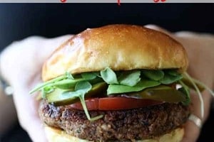 Pinterest graphic of a hand holding a quinoa burger with the text overlay "quinoa burger with walnuts."