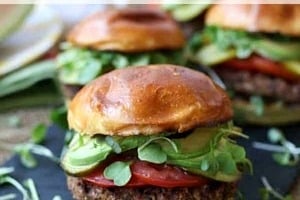 Pinterest graphic of a quinoa burger on a serving board with two more out of focus in the background with the text overlay "vegan, gluten-free quinoa burger."