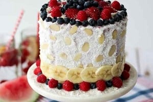 Pinterest graphic of a cake with an assortment of fruit on a cake stand with the text overlay "watermelon cake."