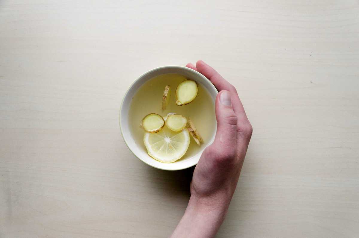 Hand holding a hot lemon and ginger tea. 