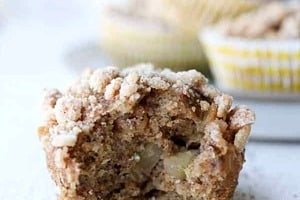 Pinterest graphic of a single muffin with a bite taken out with the text overlay "vegan apple oatmeal muffins."