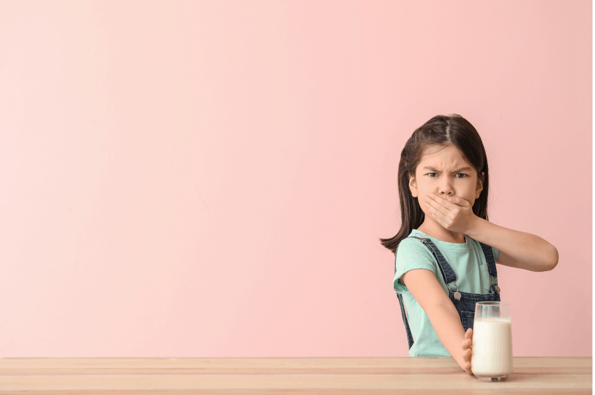 Young girl holding glass of milk and mouth.