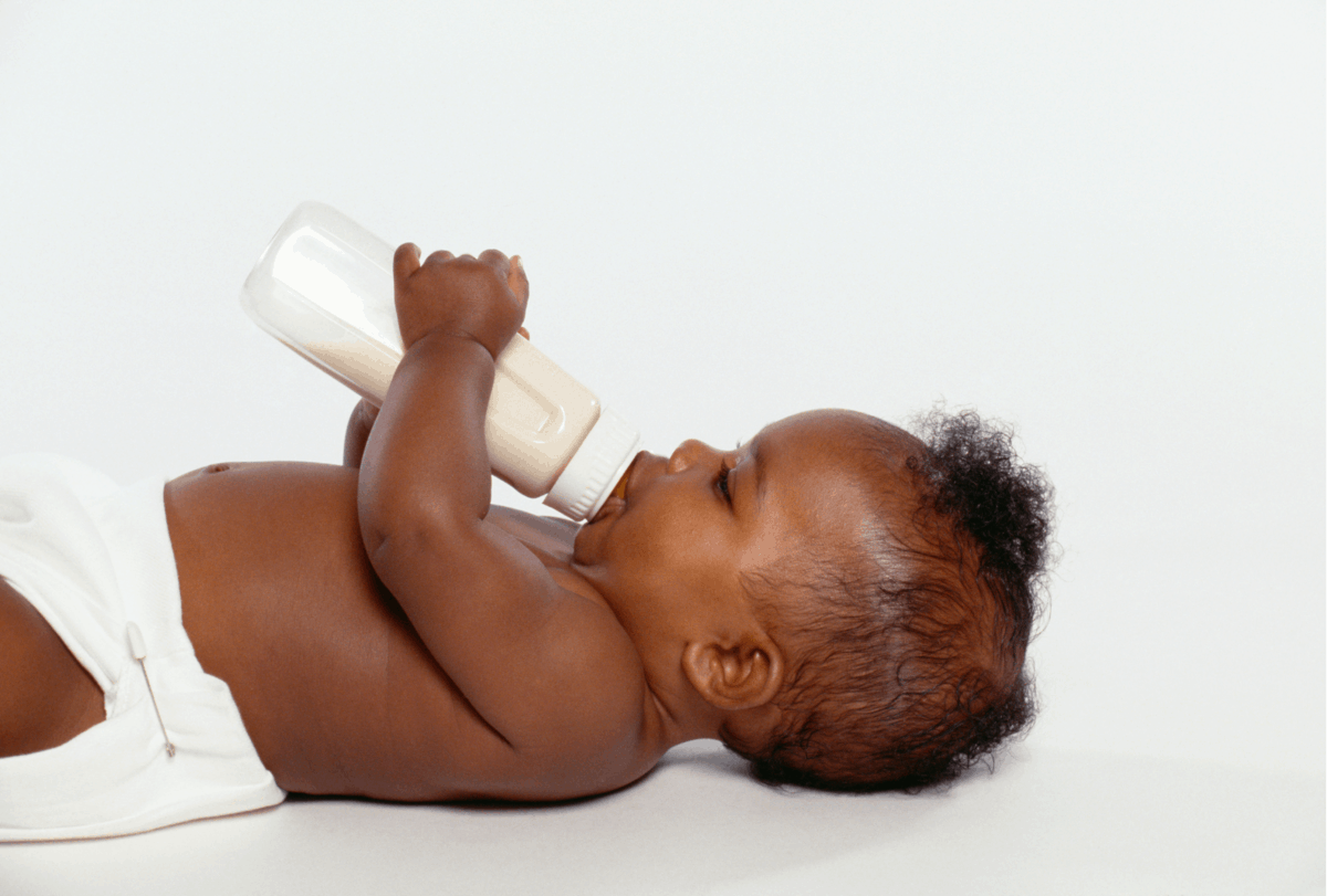 Infant laying down with bottle of milk with cows milk protein.