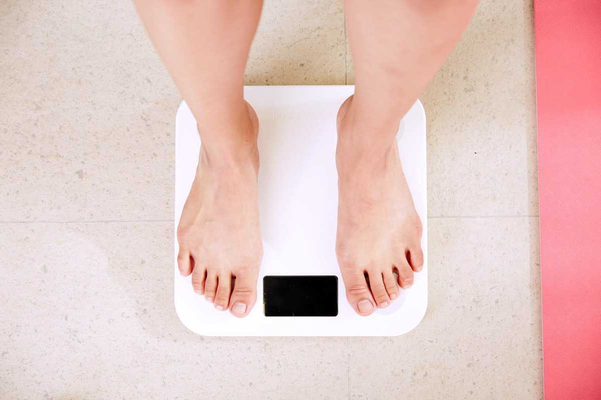 A person standing on a scale to assess weight loss.