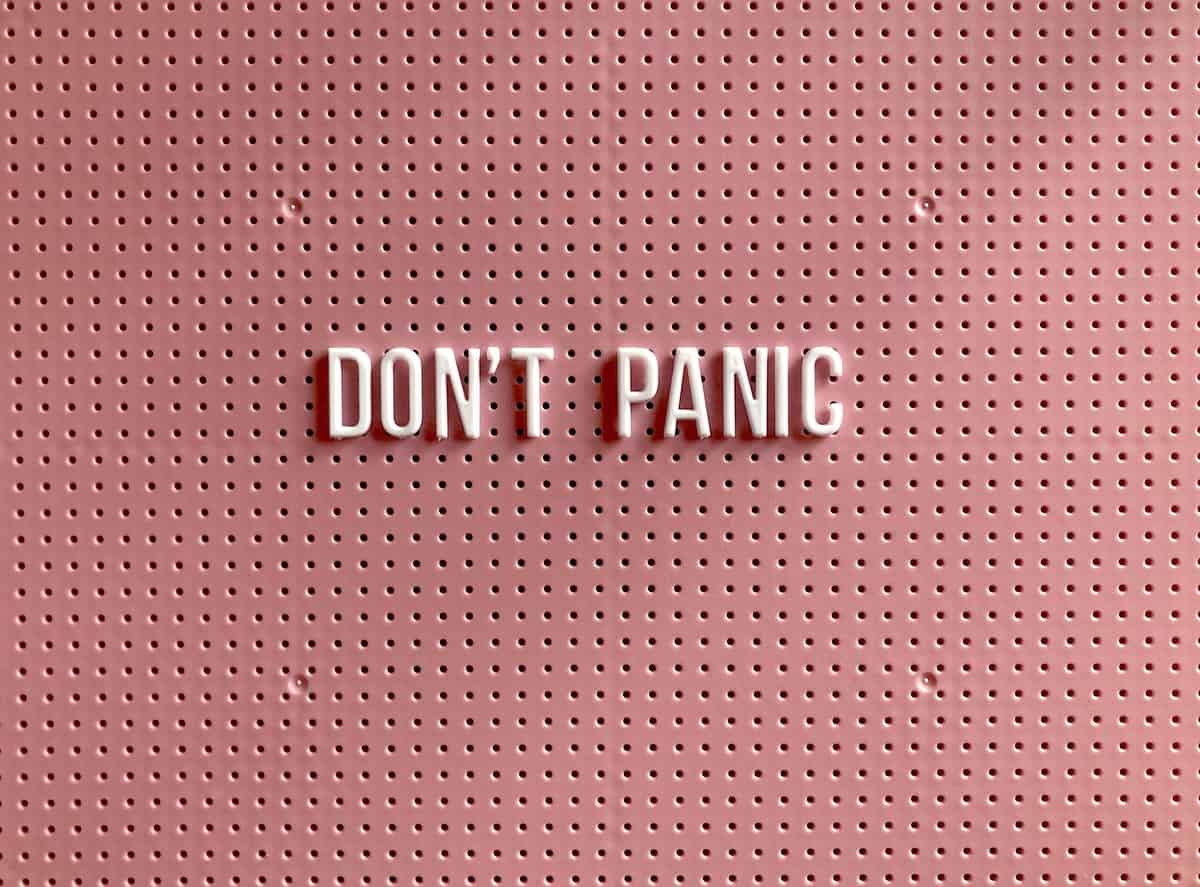 A pink background with white letters that say "don't panic".