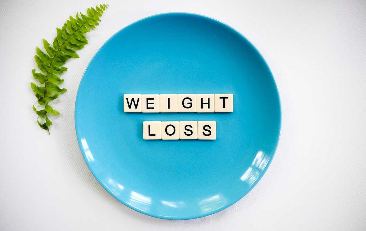 Several tiles on a blue plate spelling "weight loss".