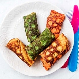 A plate with multiple coloured egg rolls on a white plate.