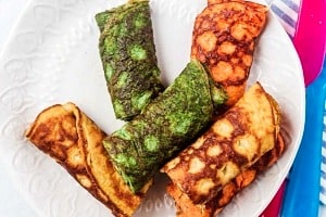 A plate with multiple coloured egg rolls on a white plate.