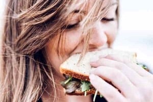 Pinterest graphic of a woman eating a sandwich with text overlay "best diet for pcos? is weight loss necessary?"