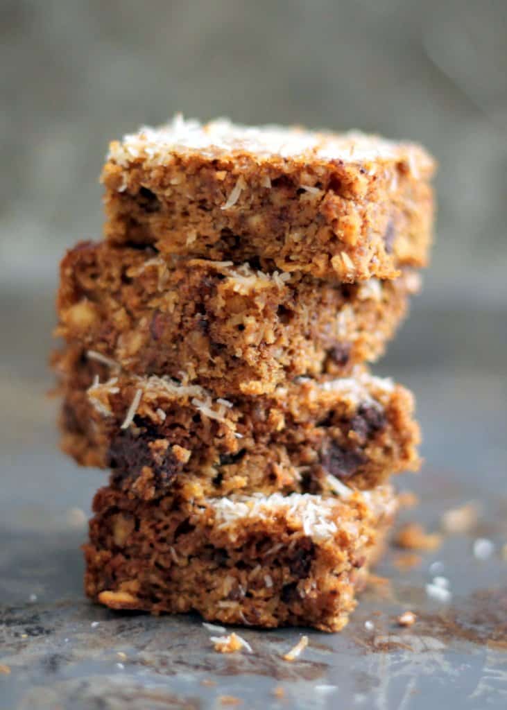 Close up of a stack of flourless pumpkin almond butter bars with dark chocolate and coconut.