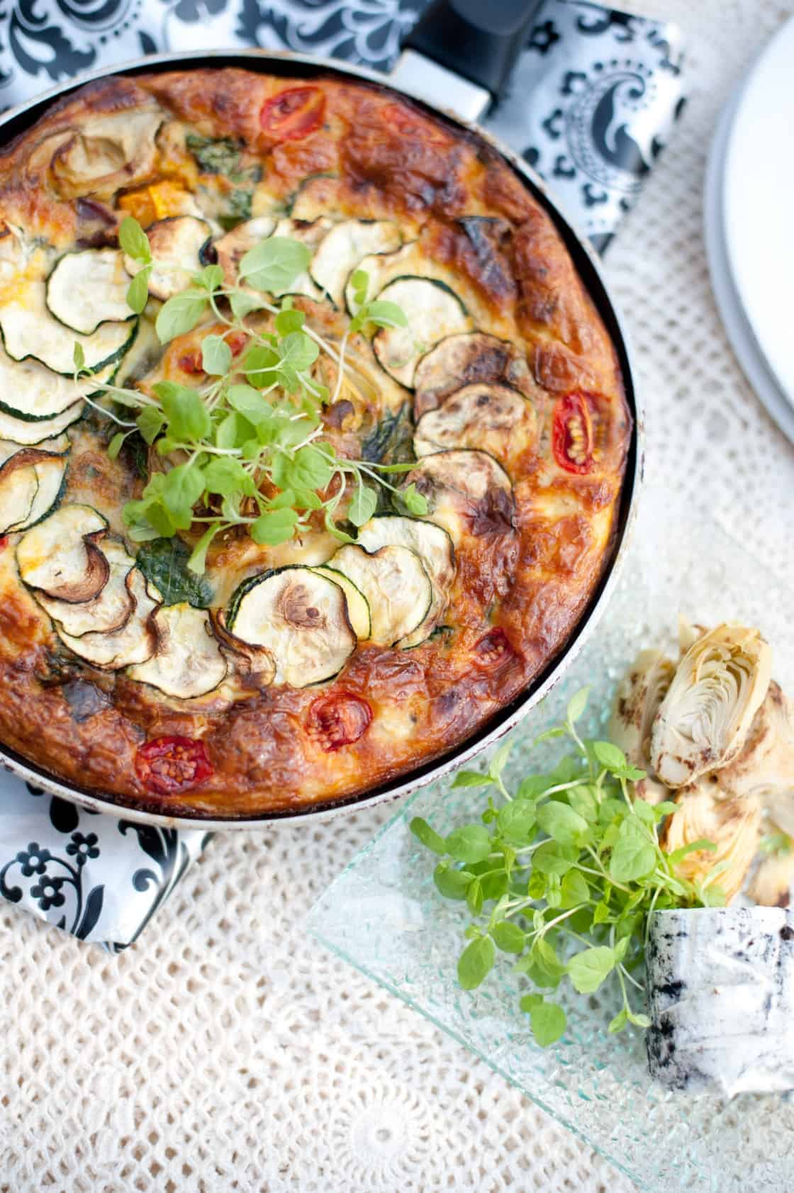 Pumpkin frittata in a skillet topped with greens.