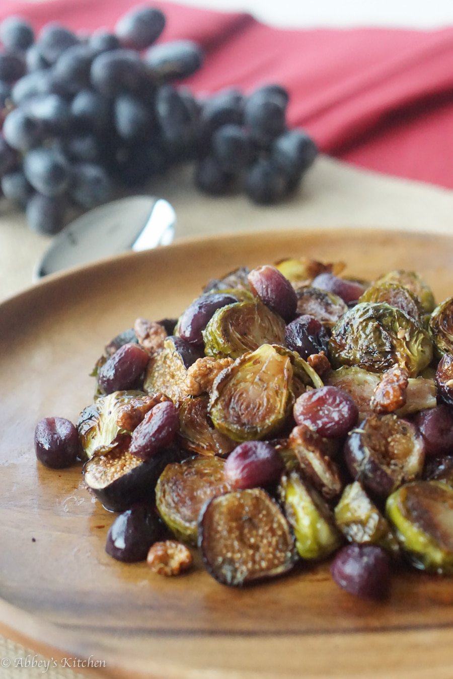 Close up of oven roasted balsamic brussels sprouts with grapes and figs  on a brown dish.