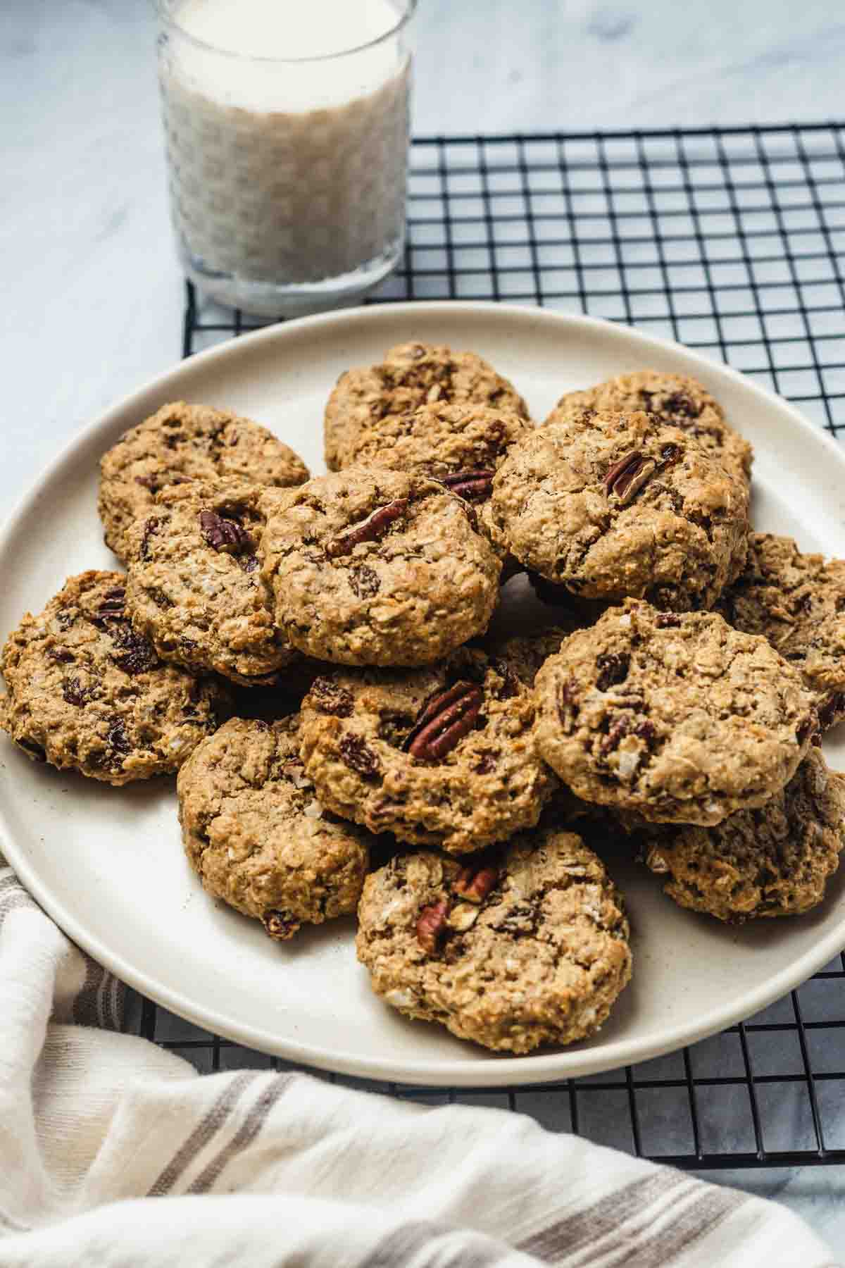 Several chai cookies on a plate on top of a cooling rack with a glass of milk in the background.