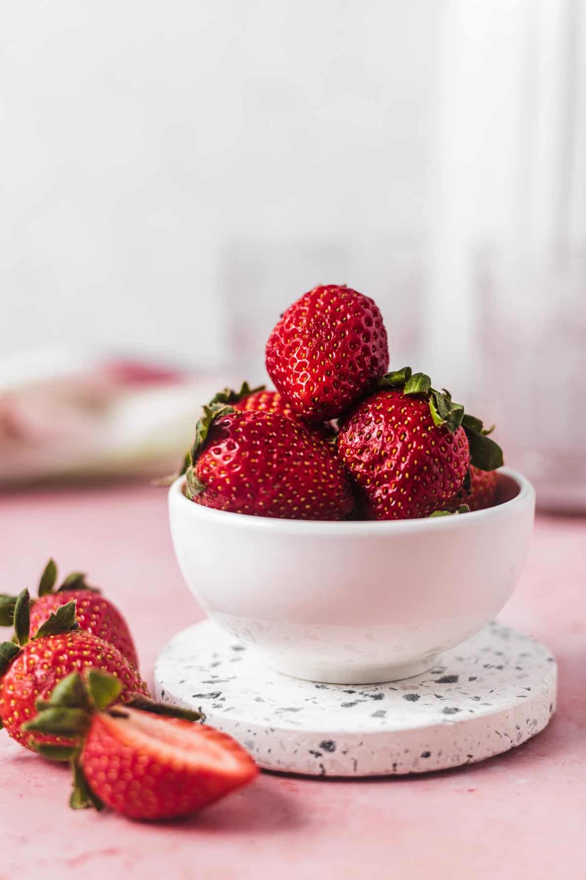 Close up of whole strawberries stacked in a white bowl.