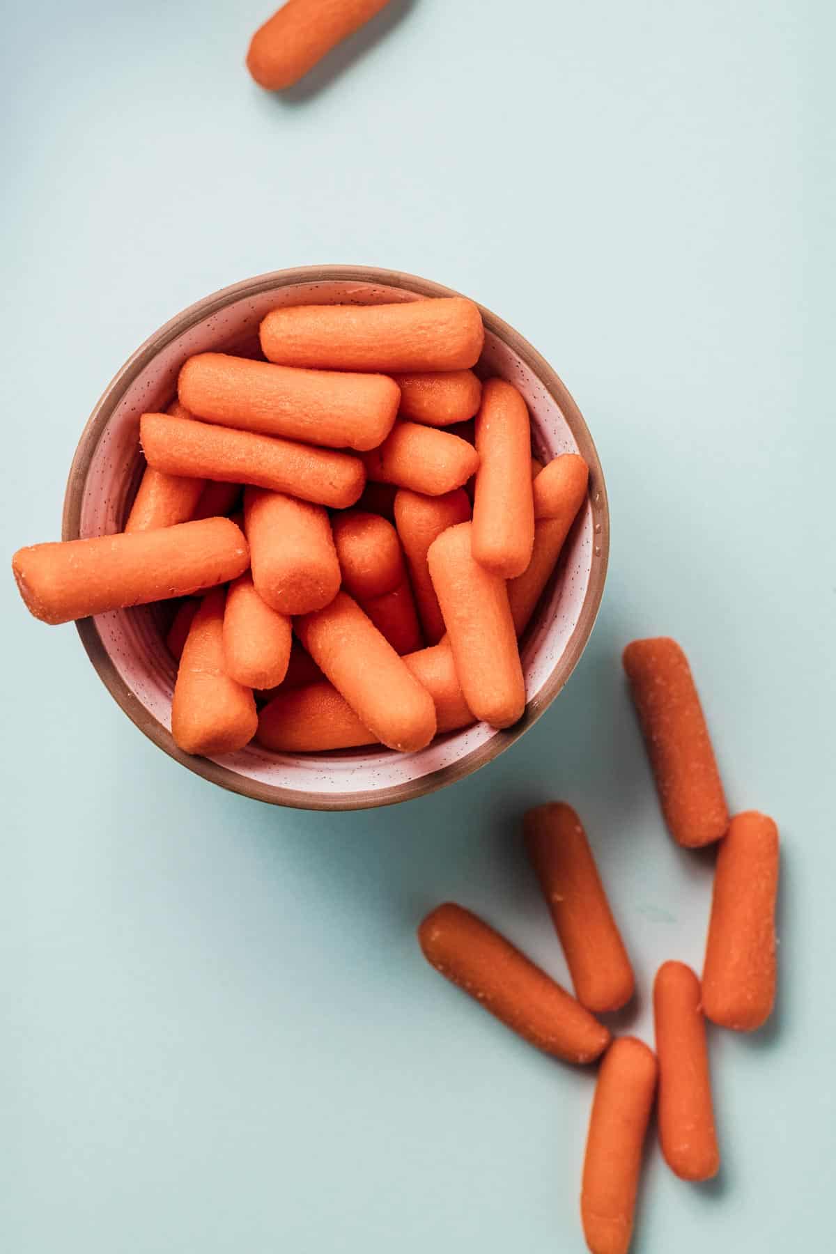 Close up of baby carrots in a pink bowl.