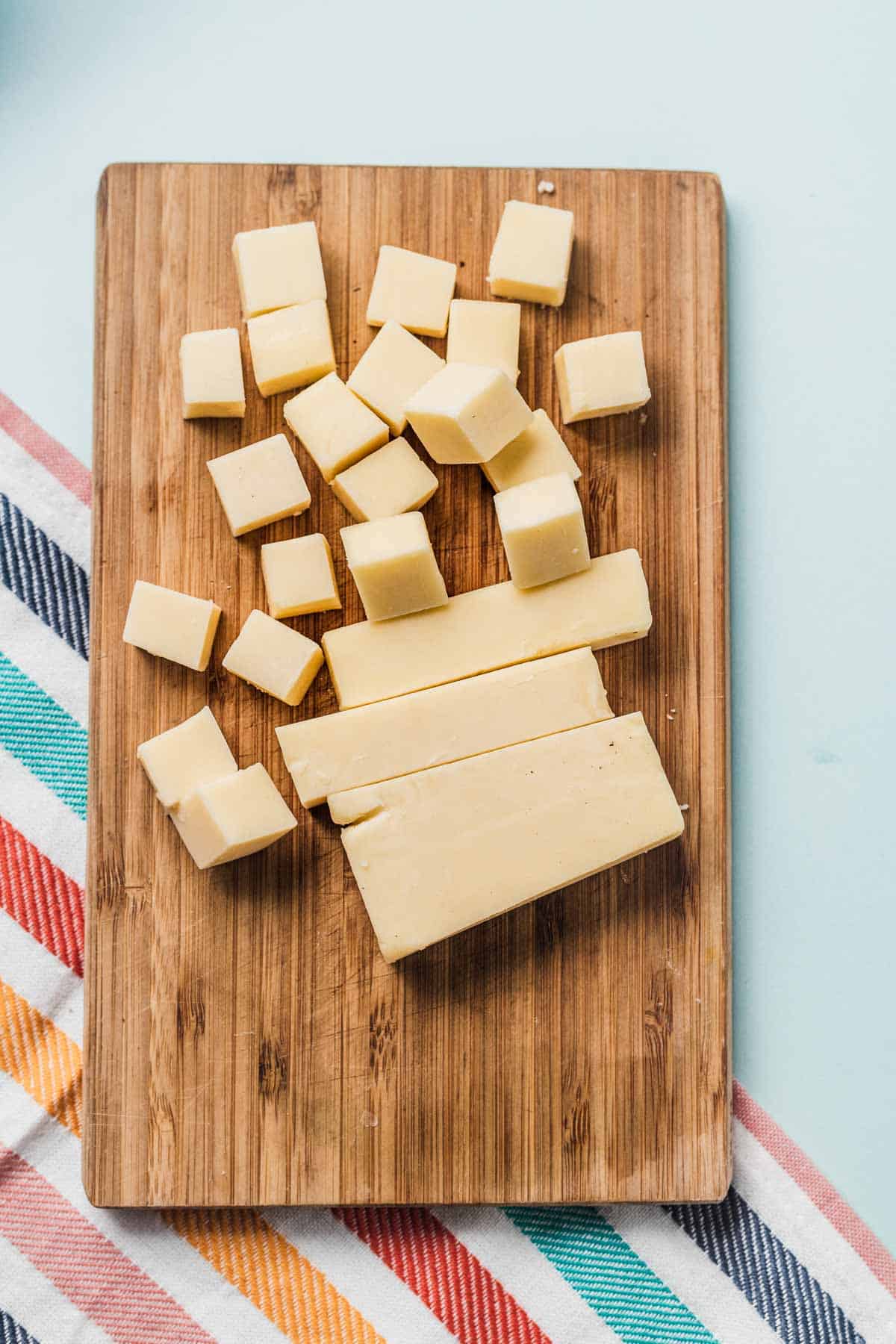 Birds eye view of cheese cubes on a wooden cutting board.