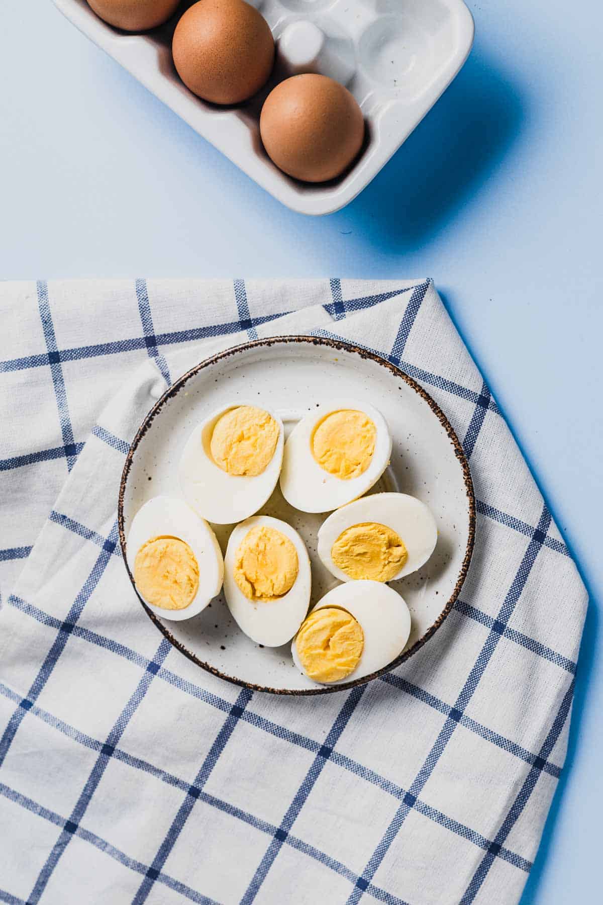 Birds eye view of 3 hard boiled eggs cut in half on a white plate.