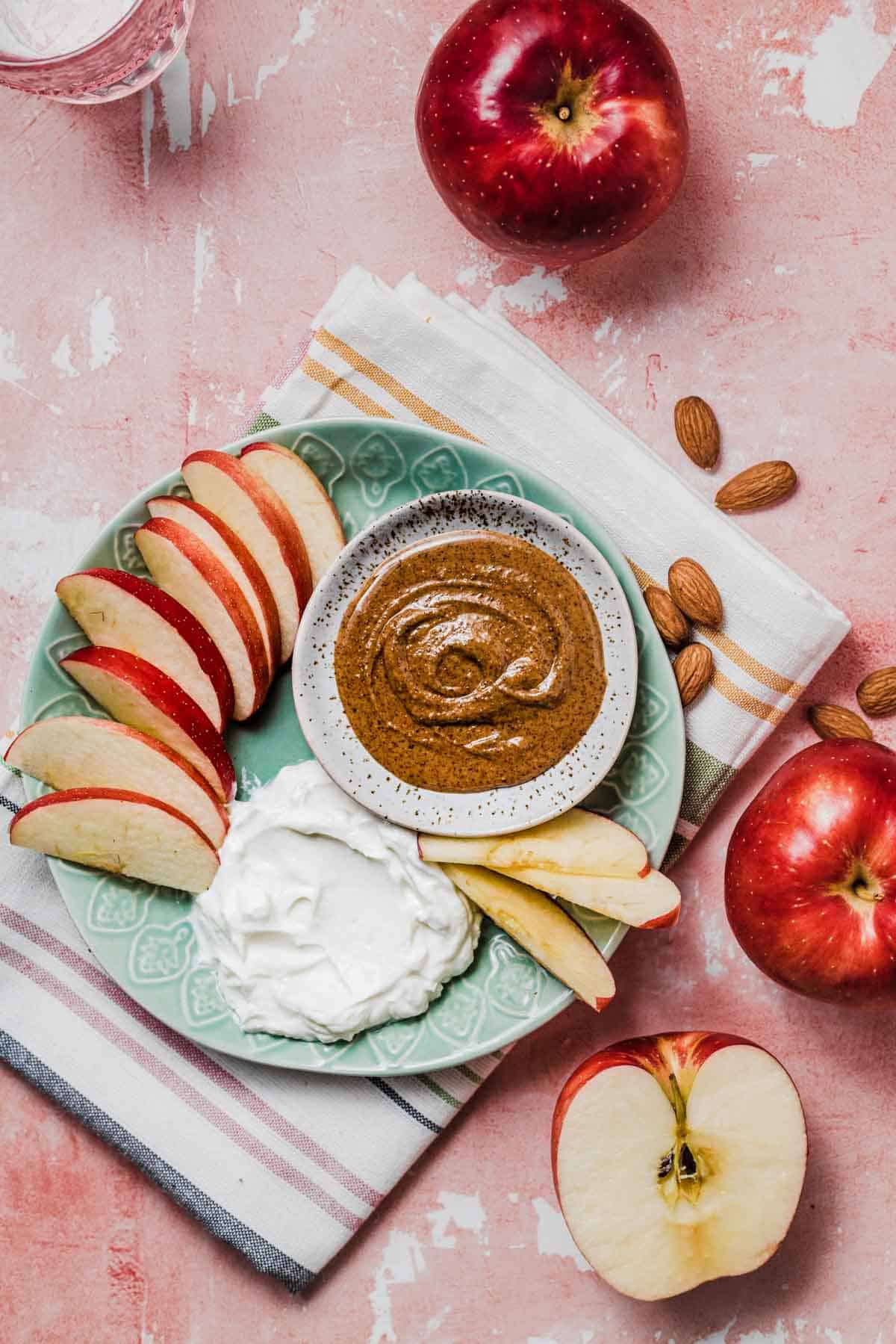 Birds eye view of sliced apple with almond butter and Greek yogurt dip on the side.
