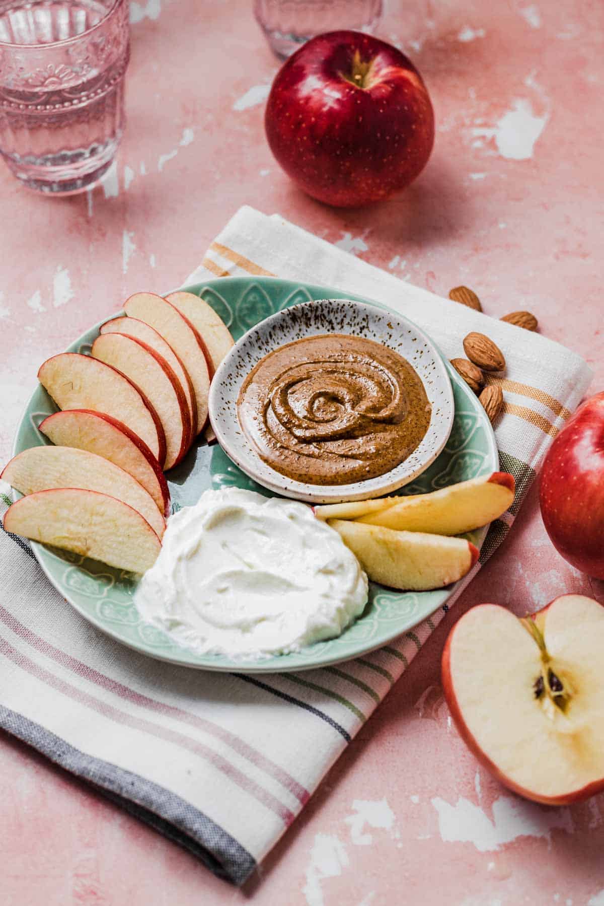 Close up image of balanced snack of sliced apples with a side of nut butter and Greek yogurt.