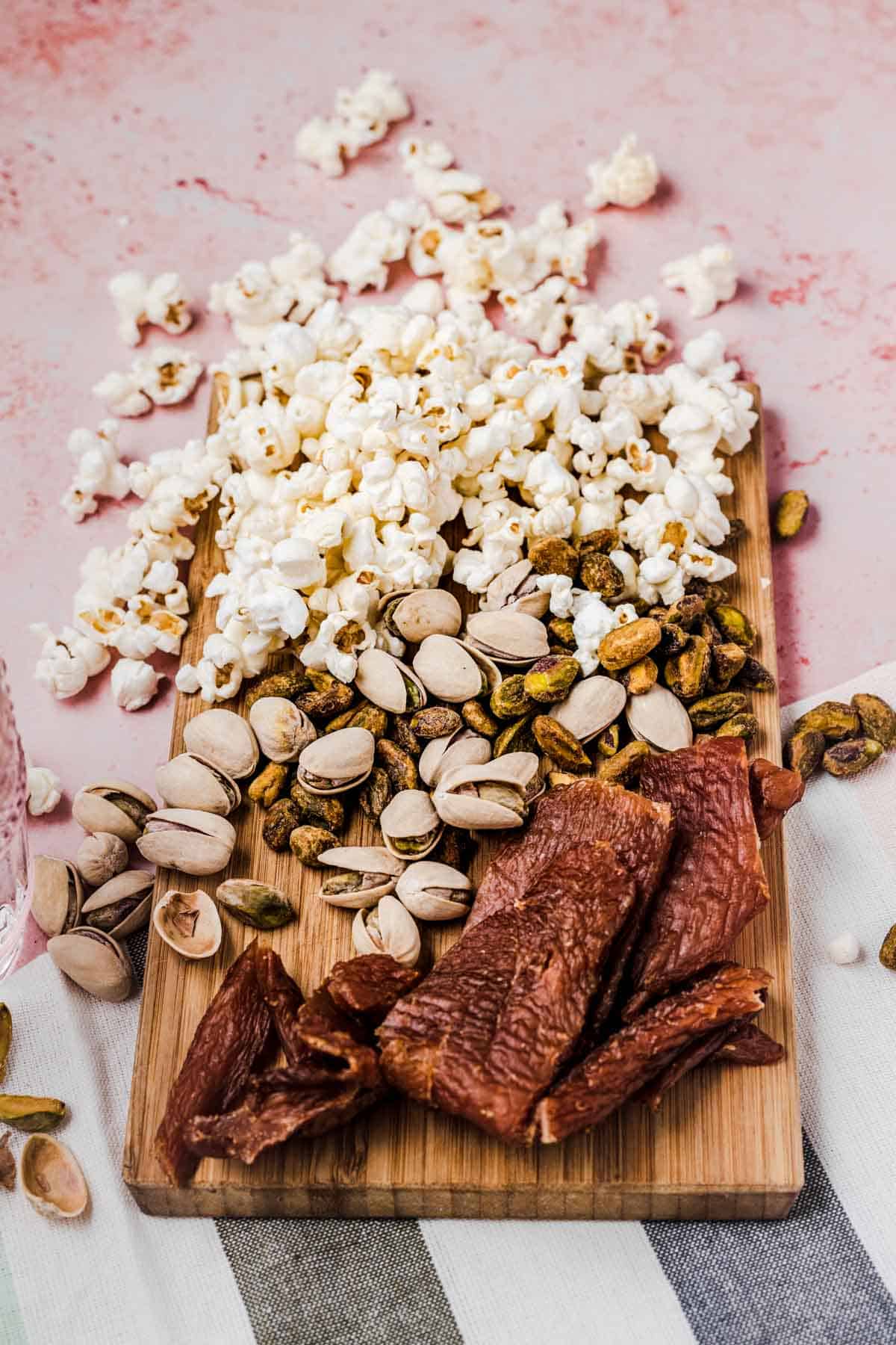 Close up of popcorn mix on a wooden cutting board.