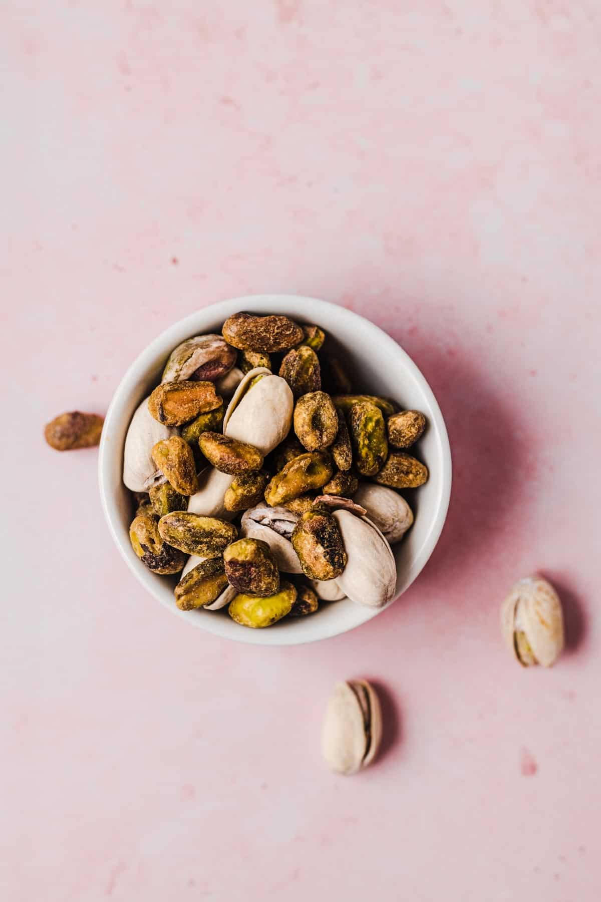 Birds eye view of pistachios in a white bowl.