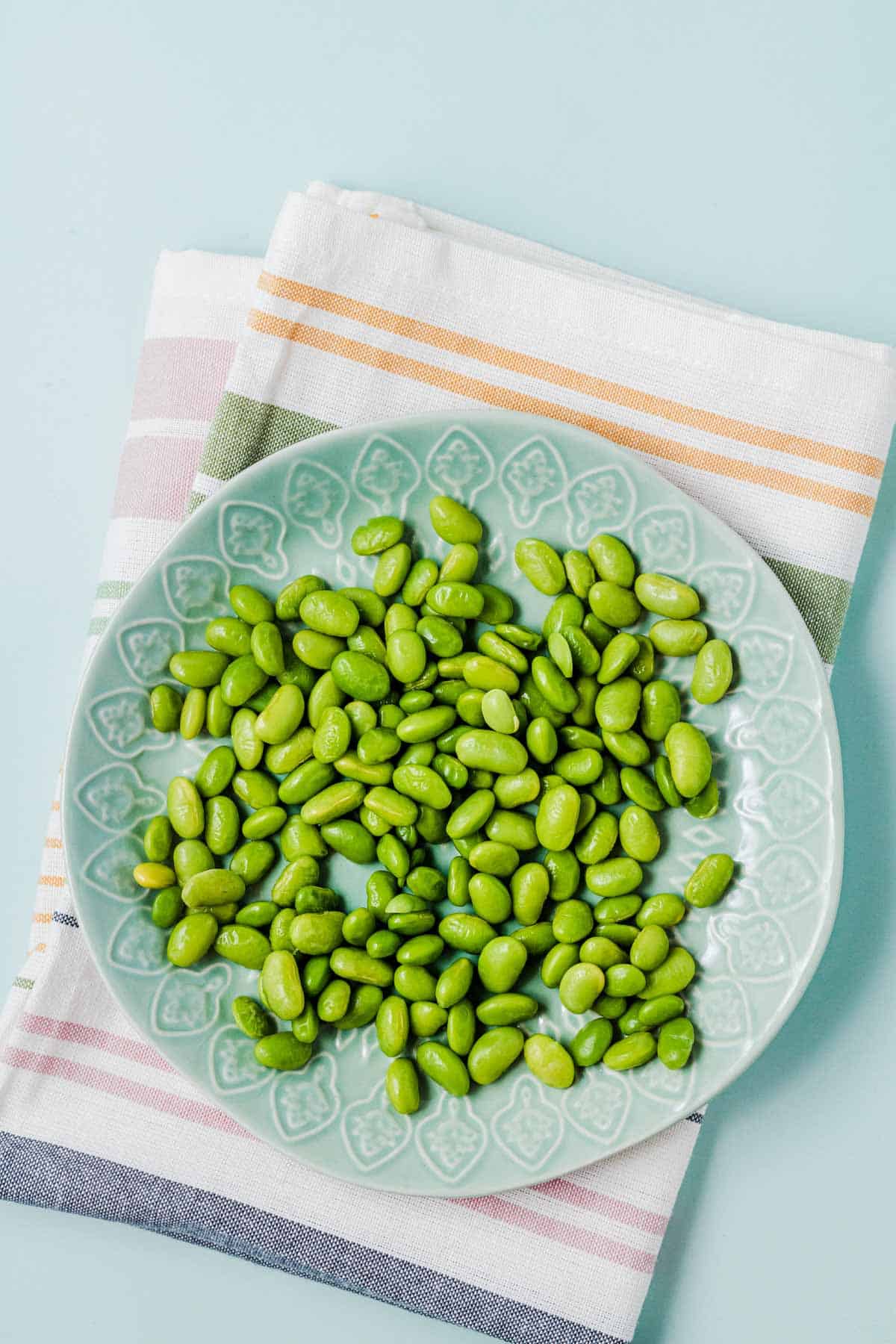 Birds eye view of edamame on a blue plate.