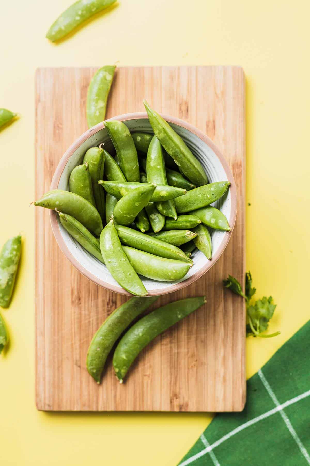 Birds eye view of sugar snap peas in a white bowl.