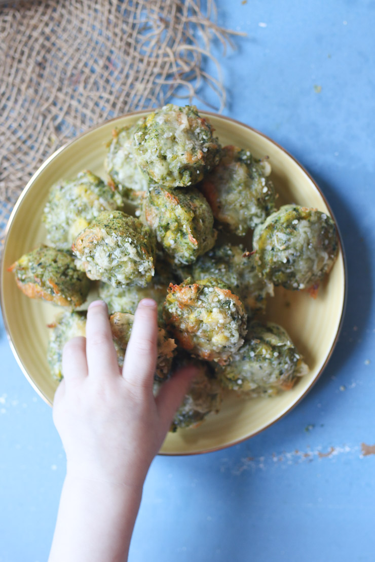 up close birds eye view of protein muffins on a yellow plate with a toddler's hand reaching for one