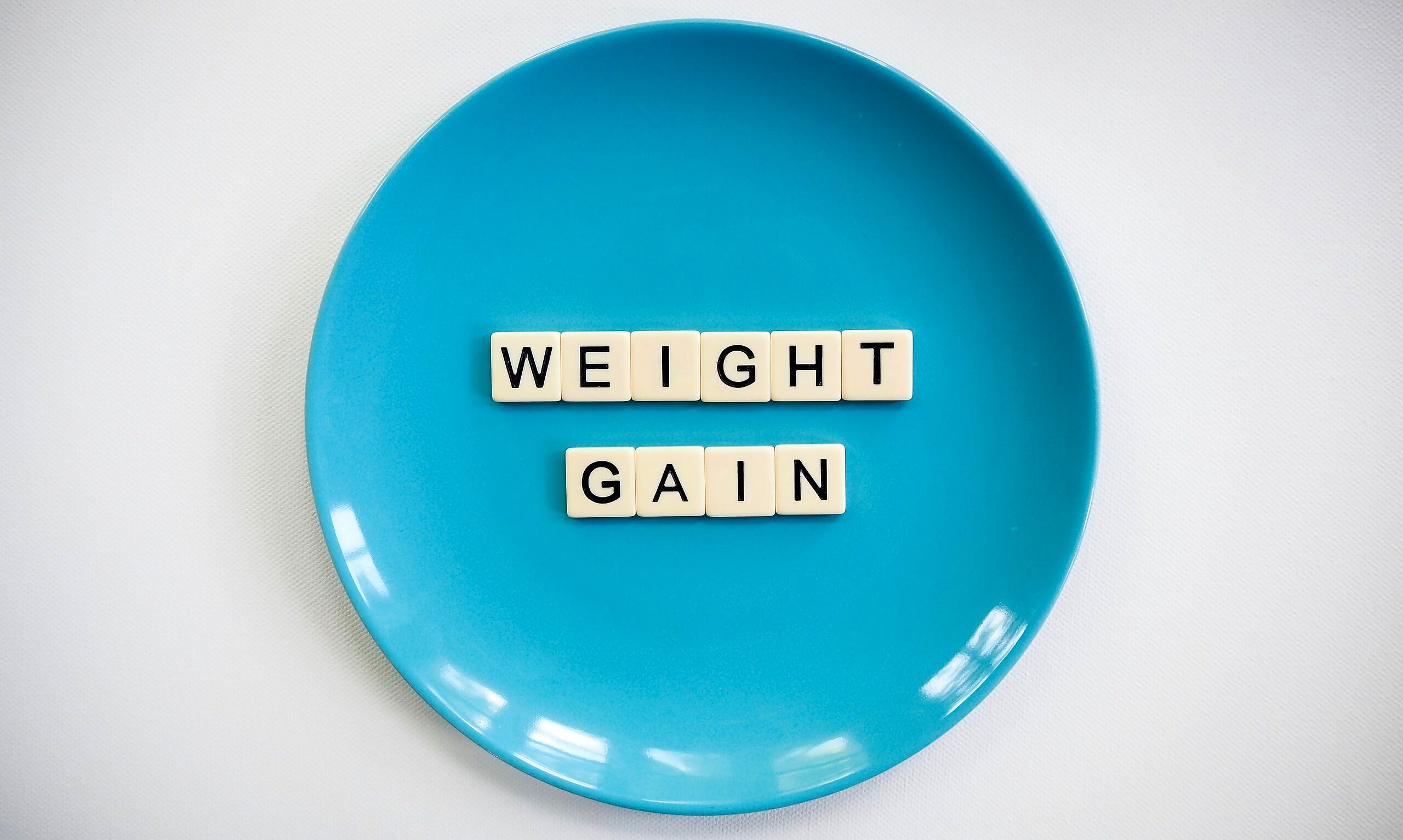 Blue plate with letters spelling the words weight gain.