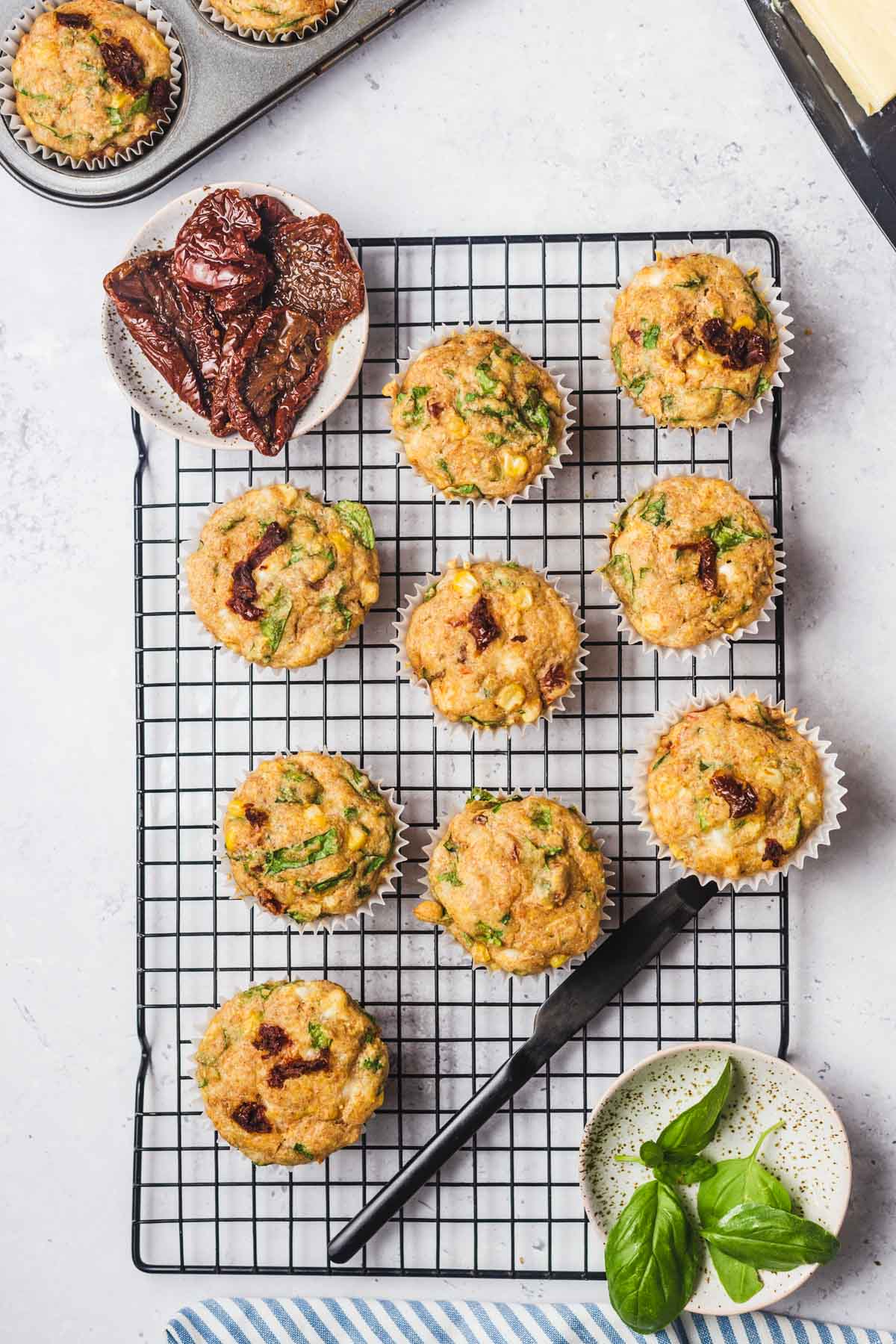 Birds eye view of savoury muffins with feta and vegetables on a cooling rack.