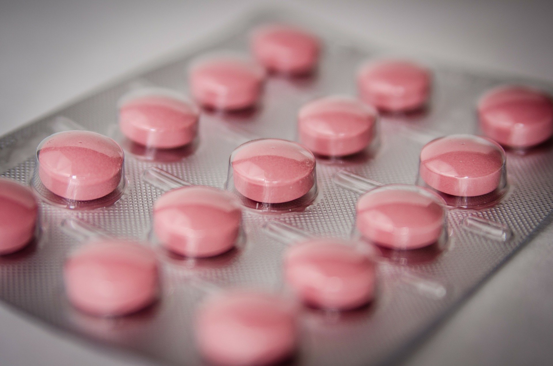An up close view of a pack of pink medicine tablets in a medicine pack.  