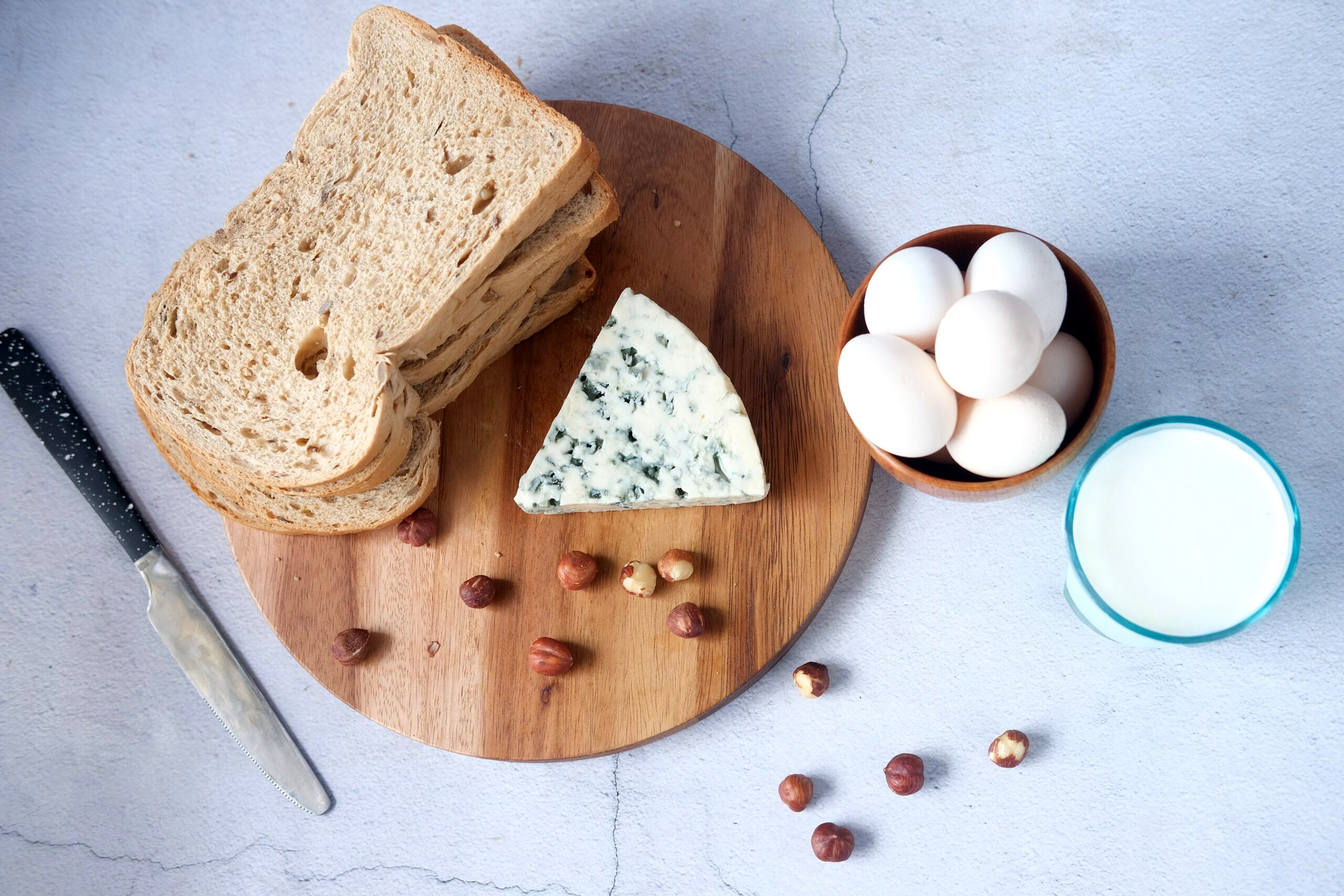 Bread and cheese on a board with nuts.