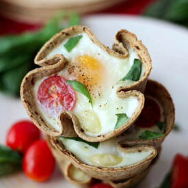 Close up of a stack of veggie egg muffins with tomatoes and basil.