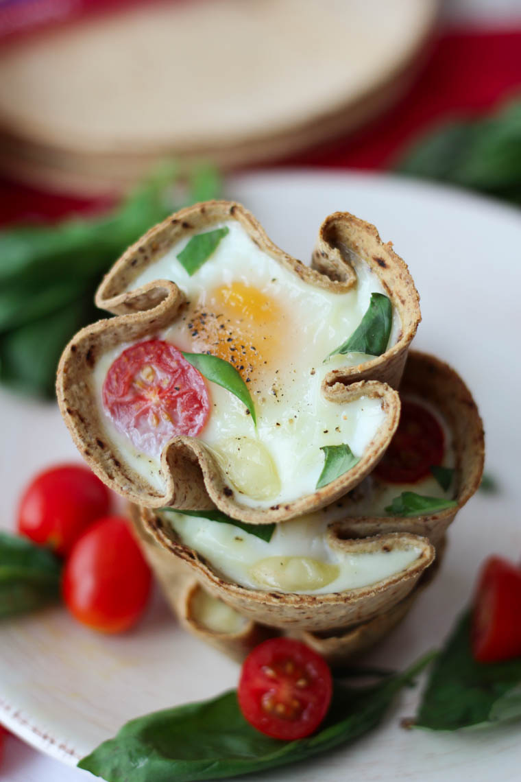 Close up of a stack of veggie egg muffins with tomatoes and basil.