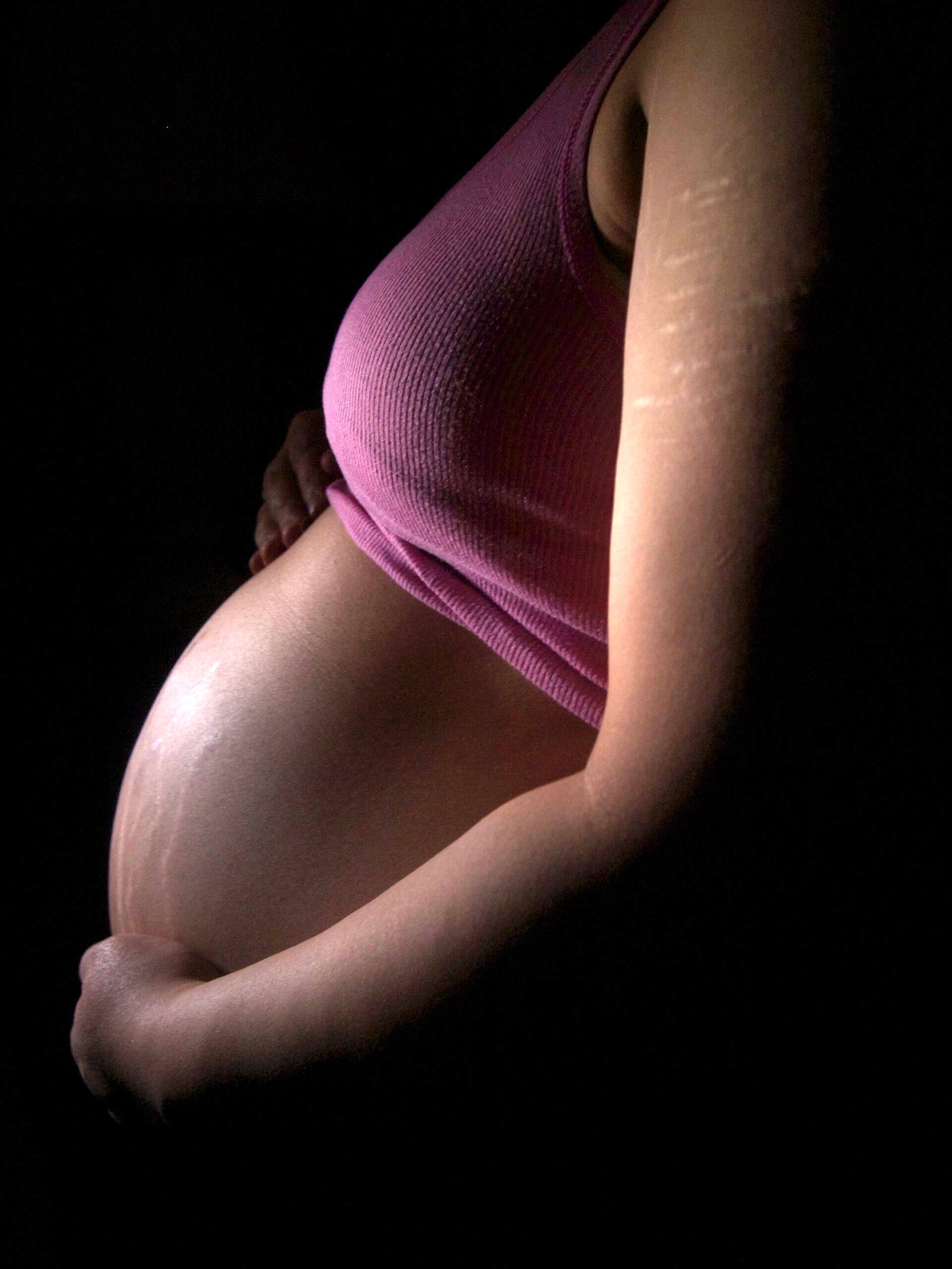 Pregnant person holding their stomach.